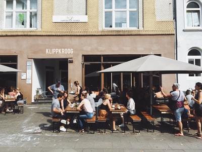 群人坐在长凳上,桌子旁边Klippkroog商店前面在白天
